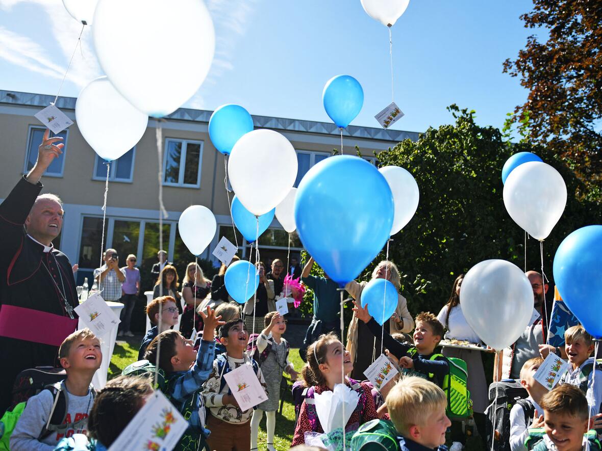 Himmelhoch jauchzend: Weihbischof Florian Wörner lässt gemeinsam mit den Erstklässlern der neuen Grundschule Luftballons steigen (Fotos: Julian Schmidt / pba)