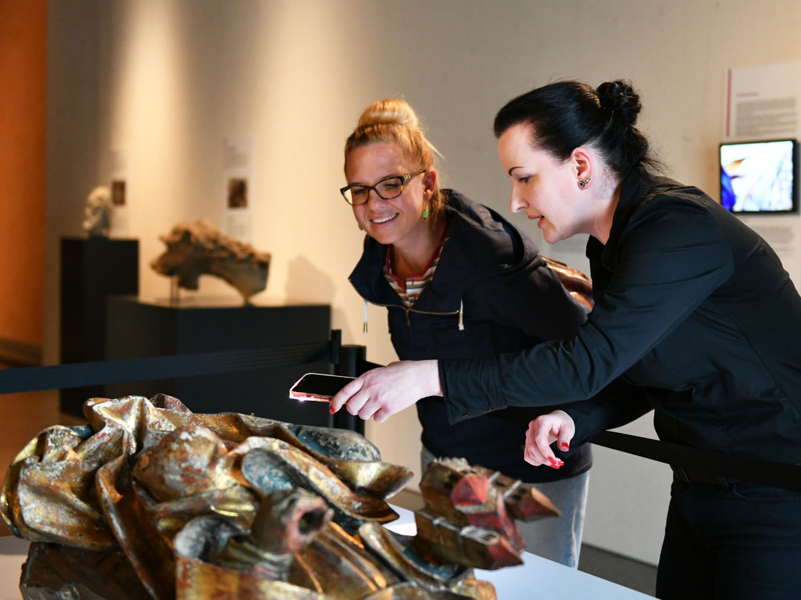 Ausstellungskuratorin Dr. Eva-Maria Bongardt (r.) erläutert die Vorgehensweise bei Restaurationsarbeiten anhand einer spätgotischen Holzskulptur des hl. Wolfgang.